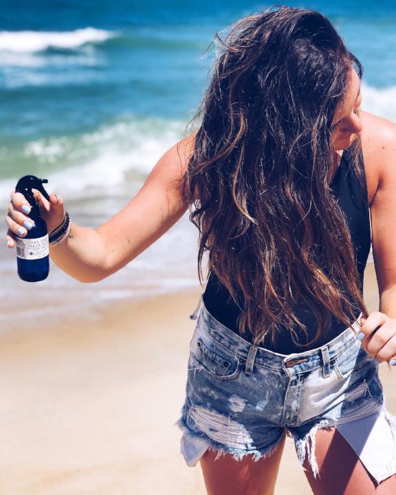 Woman on beach using vegan, plant based, cruelty free East Falls Sea Salt Hair Mist